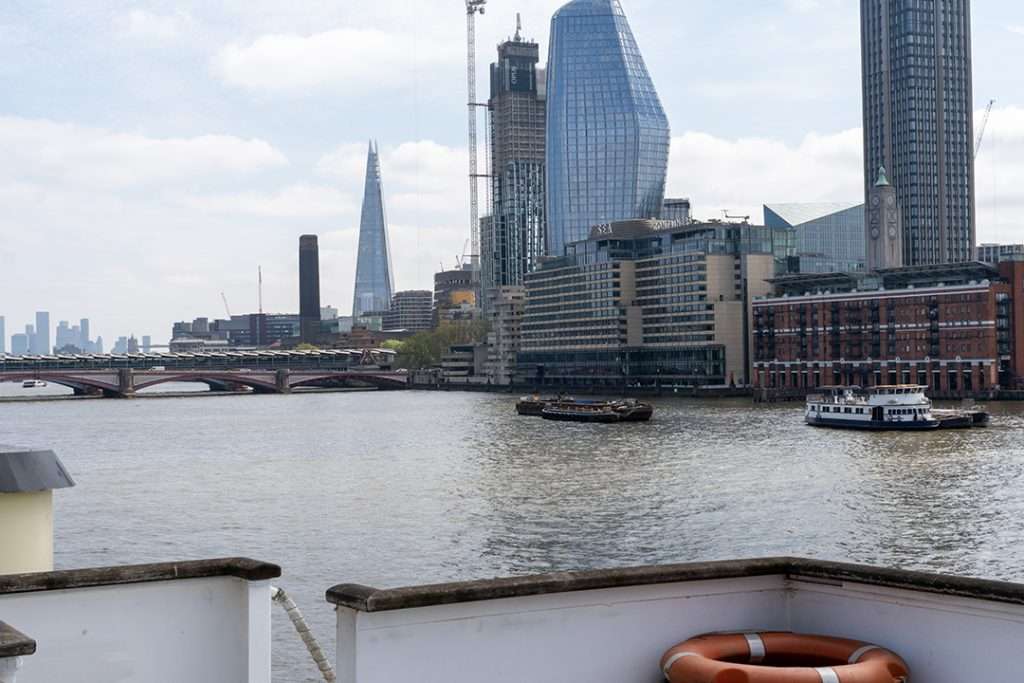 View of the London skyline from the River Thames showing the Shard and city buildings, as seen from the deck of HMS Wellington