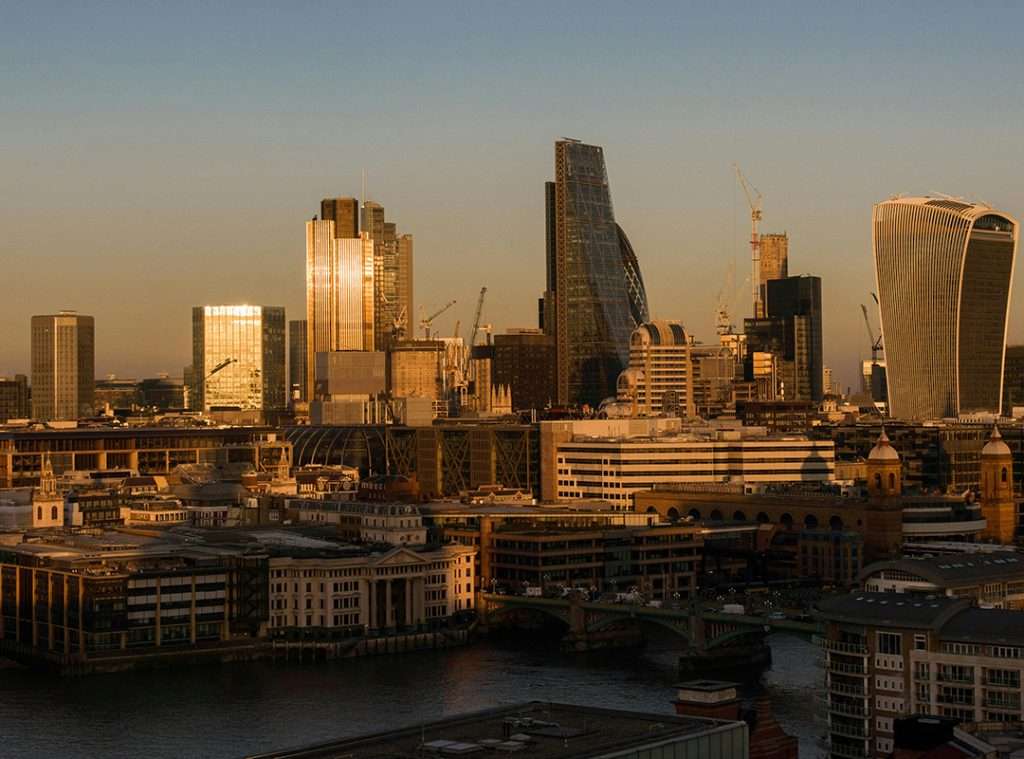 View of the London skyline with tall buildings at sunset over the River Thames, as seen from HMS Wellington